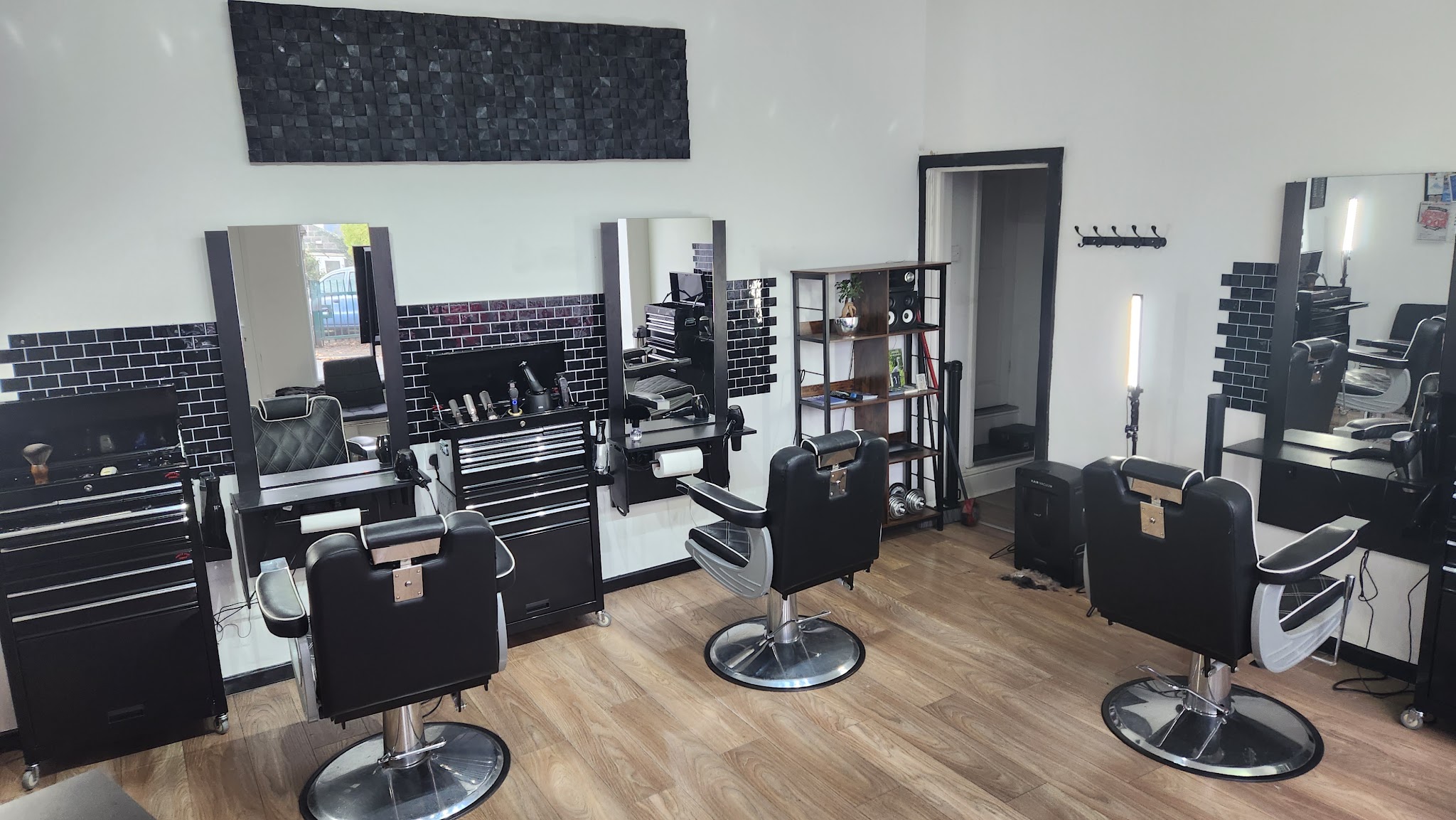 Inside our Town Street shop, with black barber chairs, tiled stations and wooden floors